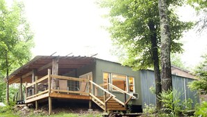 A rustic cabin with a wooden deck and a covered porch. - Private 50 ft waterfall. Eco-friendly, cozy shipping container cabin (Tracy City)