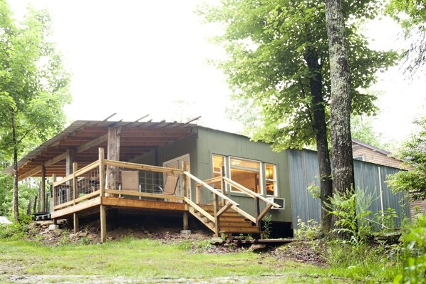 A rustic cabin with a wooden deck and a covered porch. - Private 50 ft waterfall. Eco-friendly, cozy shipping container cabin (Tracy City)