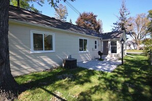 A single-story house with a covered porch, a small front yard, and a visible air conditioning unit.