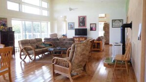 Amplia sala de estar con piso de madera, un sofá grande, una mesa de centro y un televisor.