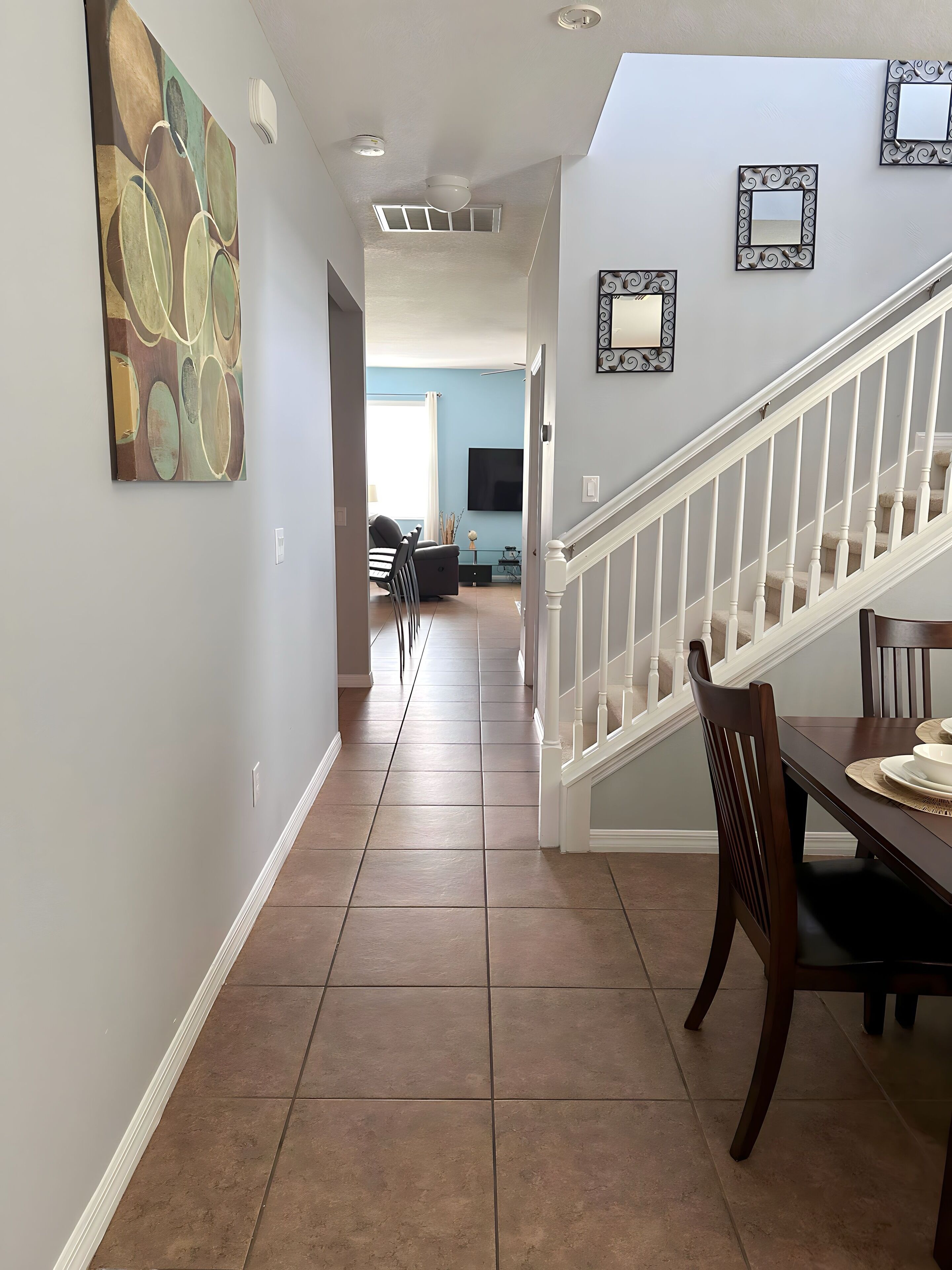 A spacious hallway with a dining area, a staircase, and a living room in the background.
