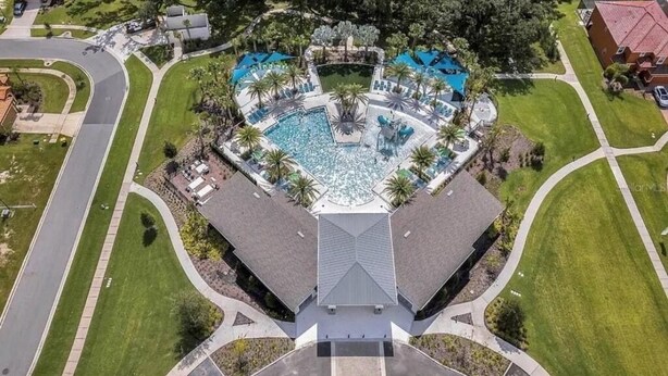 An aerial view of a hotel with a central swimming pool, surrounded by lounge chairs and palm trees. - Amazing 5 bedroom house near Disney (Kissimmee)