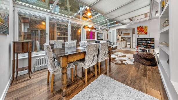 A modern dining area with a wooden table and patterned chairs, a glass ceiling, and a cowhide rug. -  5star central zone1 -2 bed 2 bath Slps 6 superWifi  (London)