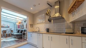 A modern kitchen with white cabinets, a stainless steel range hood, and a dining area with a sofa and table. -  5star central zone1 -2 bed 2 bath Slps 6 superWifi  (London)