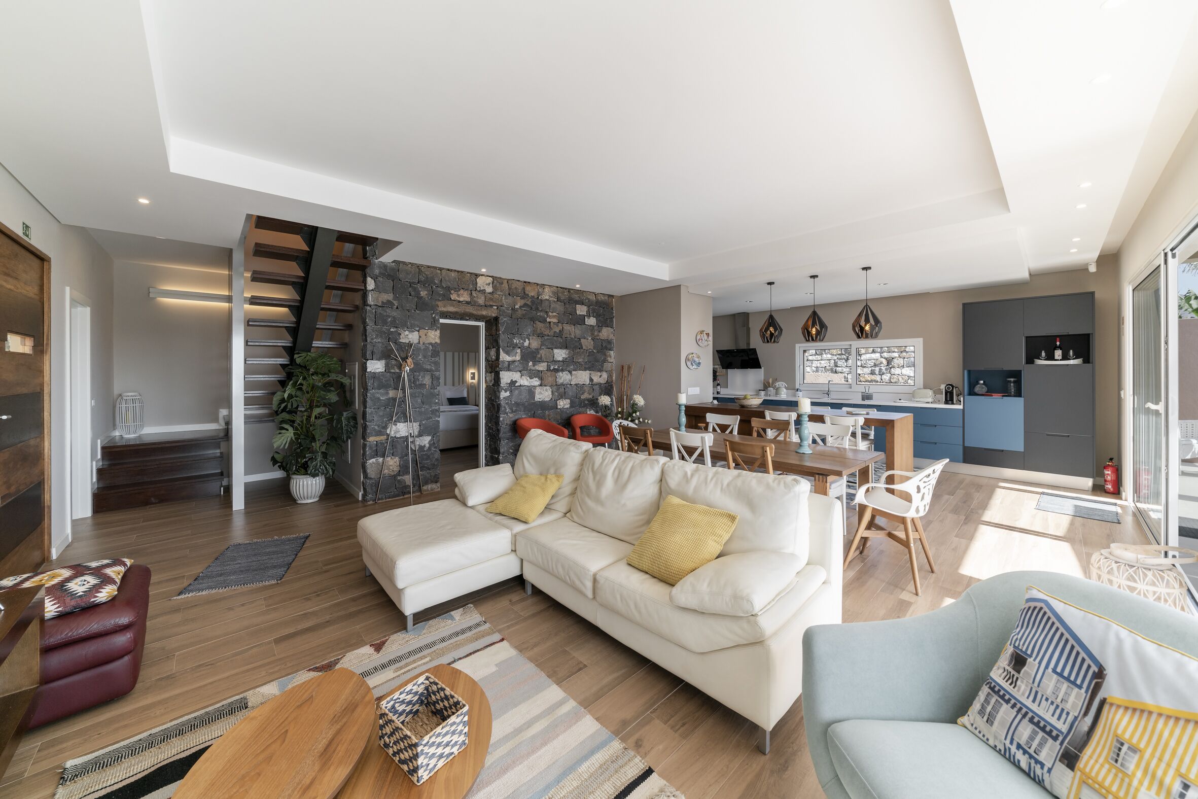 A modern living room with a sofa, a coffee table, and a dining area with chairs and a table.