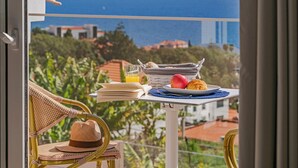 Ein Balkon mit einem Frühstückstisch, komplett mit einem Teller Croissants, einem Apfel und einem Glas Orangensaft.
