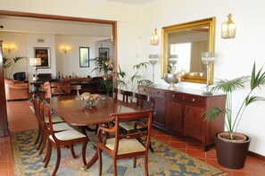 A dining area with a wooden table, chairs, a large mirror, and potted plants. - Villa Belo Horizonte (Caniço)
