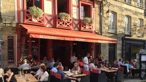 Ein Restaurant im Freien mit Korbmöbeln und einer roten Markise.
