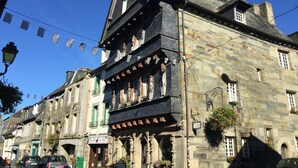 Ein historisches Steinhaus mit traditioneller Fassade, zahlreichen Fenstern und einem Schild für ein Restaurant.