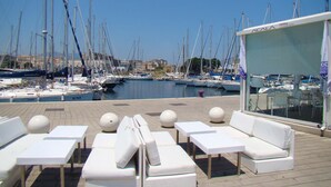A marina with multiple sailboats docked. There are lounge chairs and a covered area with a sign indicating a food and lounge bar. - At Kalsa Quiet & Flowered Terrace Free Parking! Ideal for remote working! (Palermo)