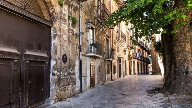 A narrow cobblestone street flanked by historic buildings with stone facades and traditional balconies. - At Kalsa Quiet & Flowered Terrace Free Parking! Ideal for remote working! (Palermo)