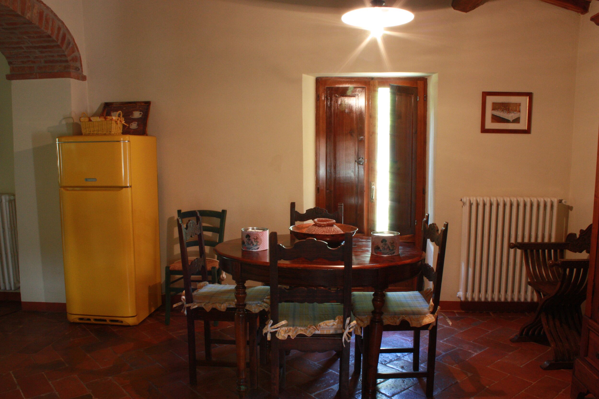 Un comedor con una mesa de madera, sillas, un refrigerador amarillo y una puerta de madera.
