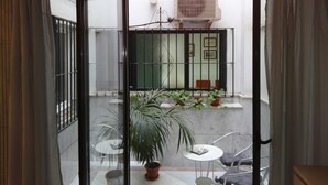 Uitzicht vanaf een balkon met een glazen deur, een plant in pot, een tafeltje en een stoel.