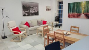 Een moderne woonkamer met een bank, stoelen, een eettafel en kunstwerken aan de wanden.