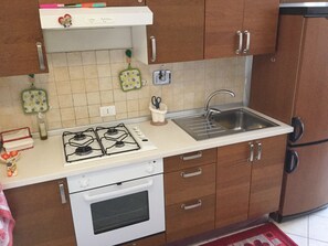 A kitchen with a gas stove, oven, sink, and wooden cabinets. - HOLIDAY IN ROME: "AN IDEAL PLACE" WITH CAR PARKING INSIDE (Roma)