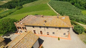A stone building with a tiled roof, surrounded by green fields and trees. - MONTEGONFOLI 2 Apartment in countryside of San Gimignano with amazing views 4+2 (san gimignano)