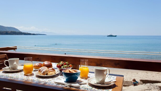 Una mesa con alimentos para el desayuno y vista al mar.