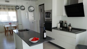 Una cocina moderna con una isla central, electrodomésticos de acero inoxidable y un televisor de pantalla plana.