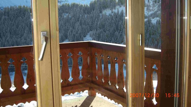 A balcony with a view of snow-covered mountains and a forest.
