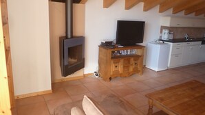 A living room with a fireplace, a television, a sofa, and a wooden table.
