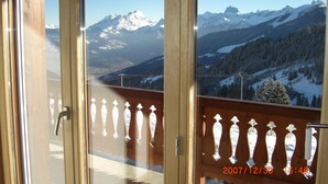 A balcony with a view of snow-covered mountains and a clear sky.