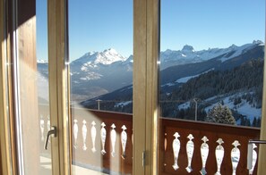 A balcony with a view of snow-covered mountains and a clear sky.
