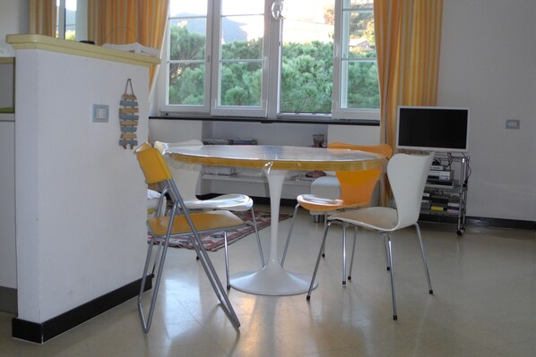 A dining area with a round table, four chairs, a refrigerator, and a television. - RELAX & LOT OF LIGHT NEAR THE BEACH (Moneglia)