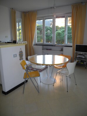 A dining area with a round table and four chairs, two yellow and two white. - RELAX & LOT OF LIGHT NEAR THE BEACH (Moneglia)
