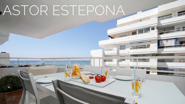 A dining area with a table set for two, overlooking a coastal view. - Astor Estepona: Lux 2BD Frontline Marina, Pool, WiFi, Sea views, Private parking (Estepona)