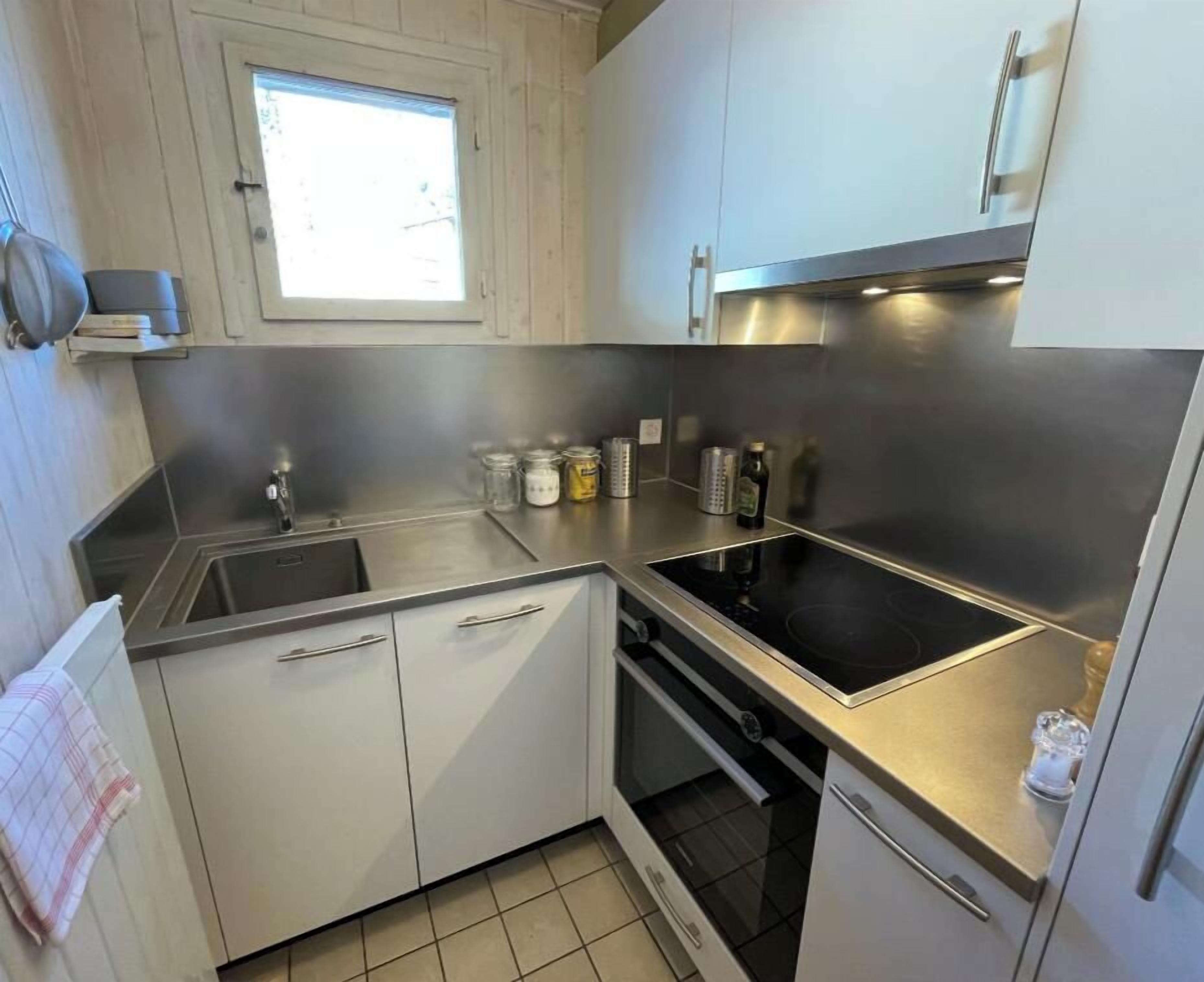Una cocina moderna con electrodomésticos de acero inoxidable, un ventanal y piso de baldosas.