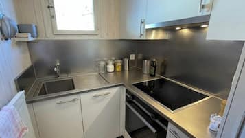 Una cocina moderna con electrodomésticos de acero inoxidable, un ventanal y piso de baldosas.