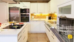 A modern kitchen with white cabinets, a built-in oven, a microwave, and a dishwasher. - Villa Meloneras Hills 16 Holiday Rentals (San Bartolome de Tirajana)
