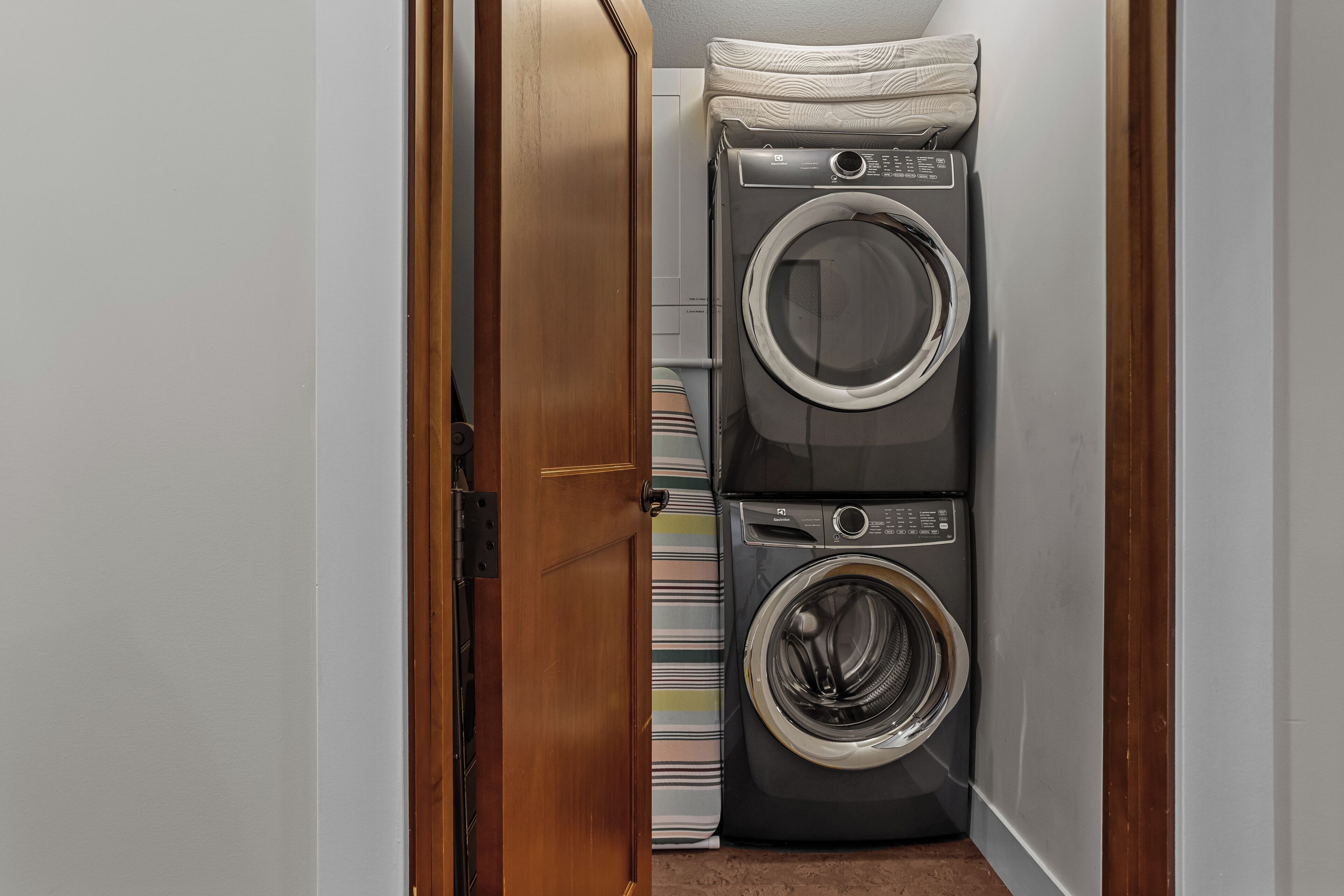 A laundry room with stacked washers and dryers, a wooden door, and a striped towel.
