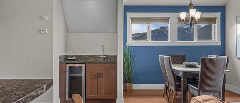 A kitchen with a built-in dishwasher, a dining area with a table and chairs, and a view of mountains through the windows.