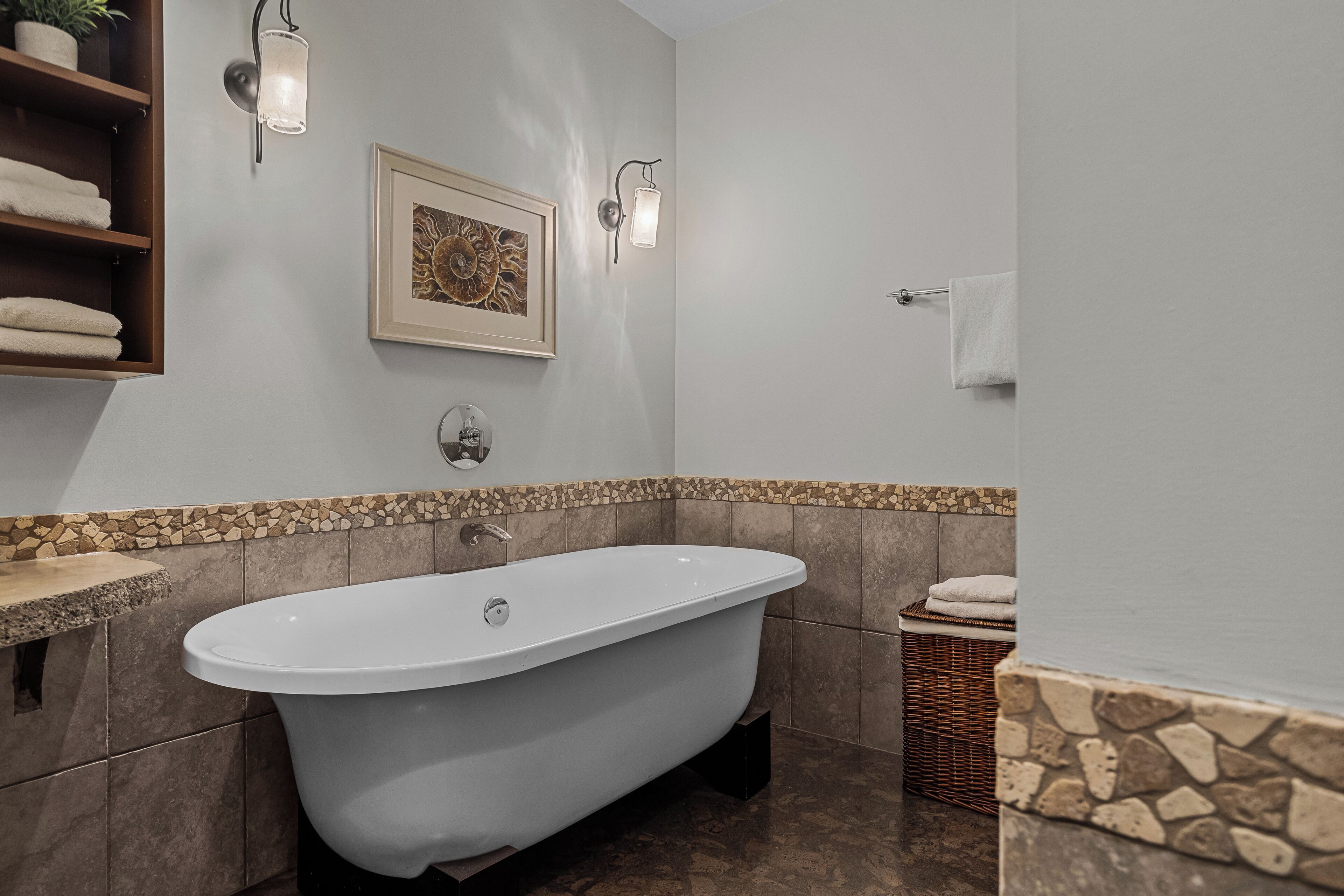 Ein modernes Badezimmer mit einer freistehenden Badewanne, einem gerahmten Kunstwerk und einem Handtuchhalter.