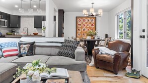 A modern living room with a grey sofa, a brown leather chair, and a dining area with a table and chairs. - Outpost: Clark's Knoll 385 - Walk to Town Square (Jackson)