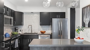 A modern kitchen with dark cabinetry, stainless steel appliances, and a central island. - Outpost: Clark's Knoll 385 - Walk to Town Square (Jackson)
