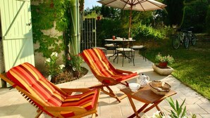 A patio area with two striped lounge chairs, a table with a teapot and cups, and an umbrella. - Charming cottage ****, near Montpellier and 20 'beaches (Prades-Le-Lez)