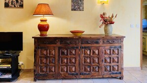 A wooden cabinet with multiple drawers, a television on a stand, and a vase with dried plants on top. - Charming cottage ****, near Montpellier and 20 'beaches (Prades-Le-Lez)