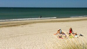 A beach with people sunbathing and a person walking along the shore. - Charming cottage ****, near Montpellier and 20 'beaches (Prades-Le-Lez)