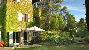 A stone building with ivy-covered walls, a patio with a table and chairs, and bicycles parked outside. - Charming cottage ****, near Montpellier and 20 'beaches (Prades-Le-Lez)