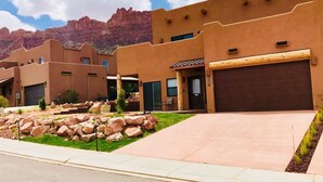 A residential area with stucco buildings, a paved driveway, and a rocky landscape. - Moab Village Luxury Retreat Gorgeous views, PVT Hot Tub, 3 STE, 3.5 BTH, 1.5 KT (Moab)