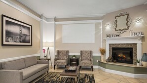 A living room with a sofa, two armchairs, a coffee table, a fireplace, a framed picture, and a decorative mirror. - WorldMark San Francisco (San Francisco)