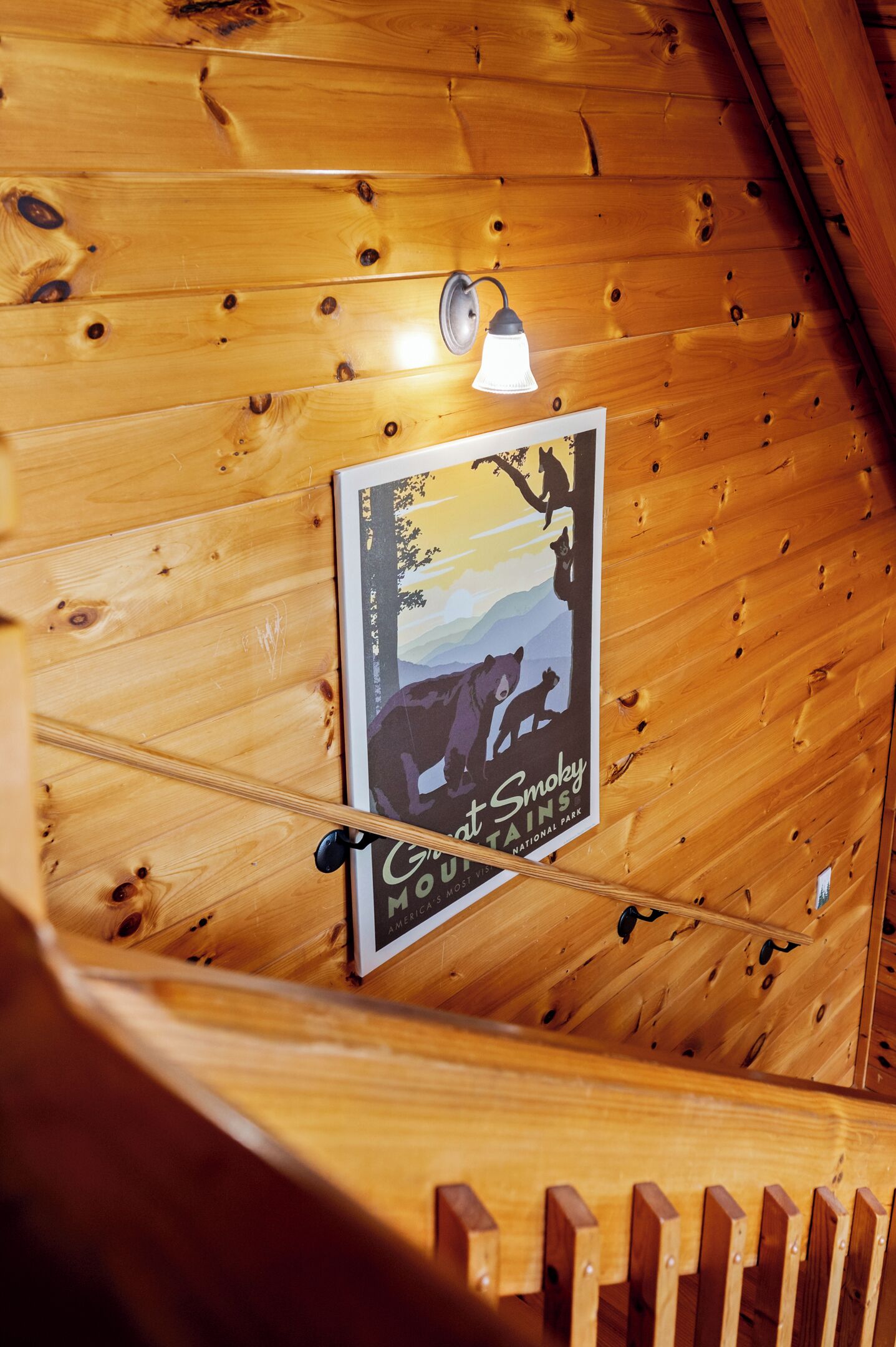 Eine Holzbalkendecke mit einem Poster vom Nationalpark Smokey Mountains, einer Lampe und einem Holzwandhandlauf.