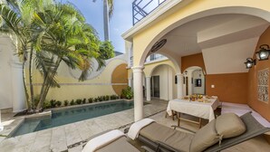 A poolside area with lounge chairs, a dining table, and a pool.