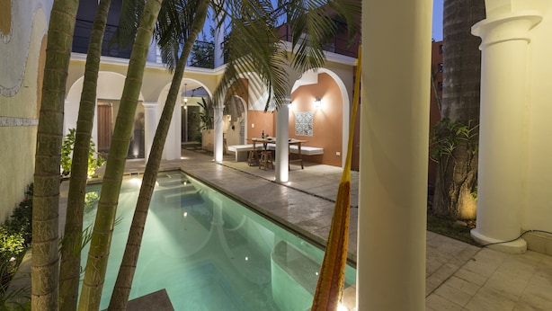 A pool area with palm trees, a dining area, and a covered walkway.