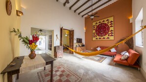 A spacious living area with a hammock, a sofa, a coffee table, and a vase of flowers.