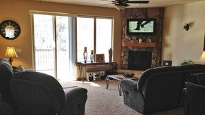 A living room with a fireplace, a television, and a ceiling fan. - Luxury Condo in Brian Head,  Beautiful Amenities,  Easy Walk/Ski To Slopes (Brian Head)