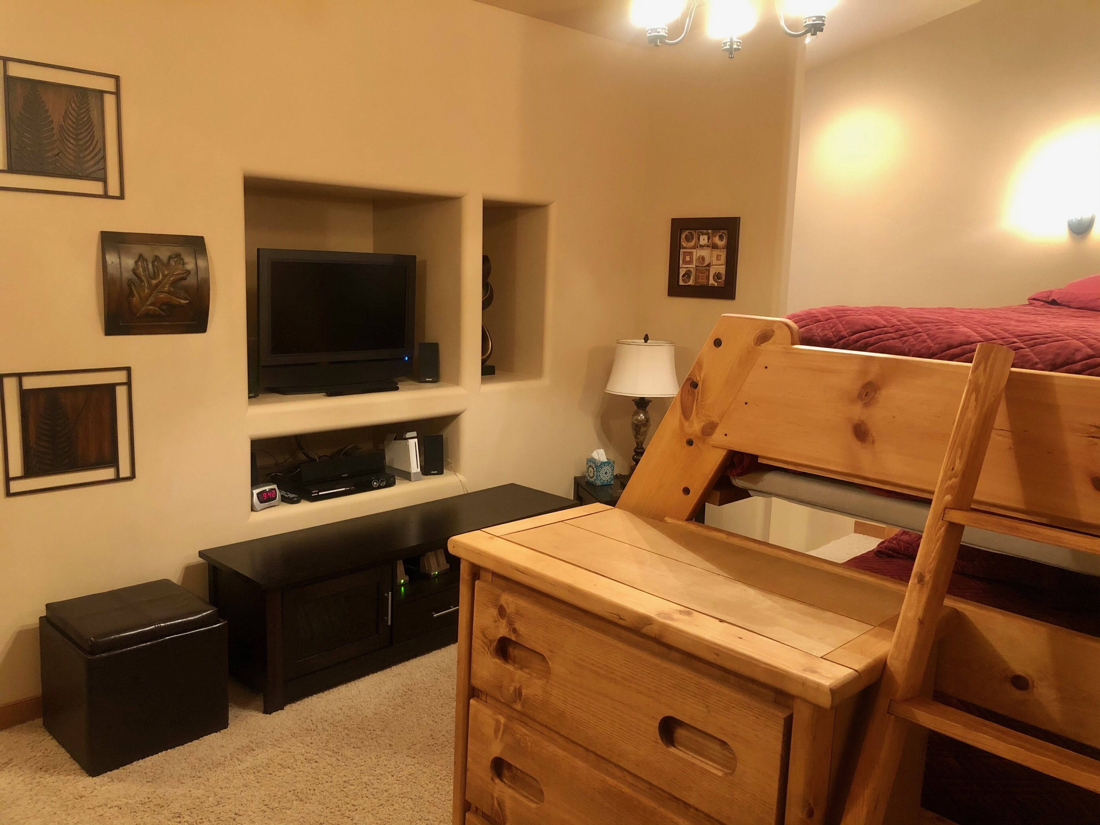 A bedroom with a bunk bed, a TV, a console table, and a dresser.