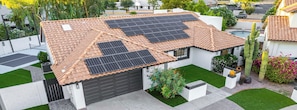 A house with a tiled roof, solar panels, a garage, and a well-maintained lawn. - Private Luxury 6BR Resort: Pool, Pickleball, Oasis (Scottsdale)